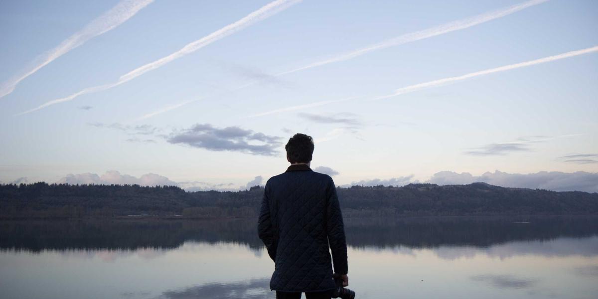 A lone figure standing on an empty beach — the isolated feeling manipulative interfaces are designed to create