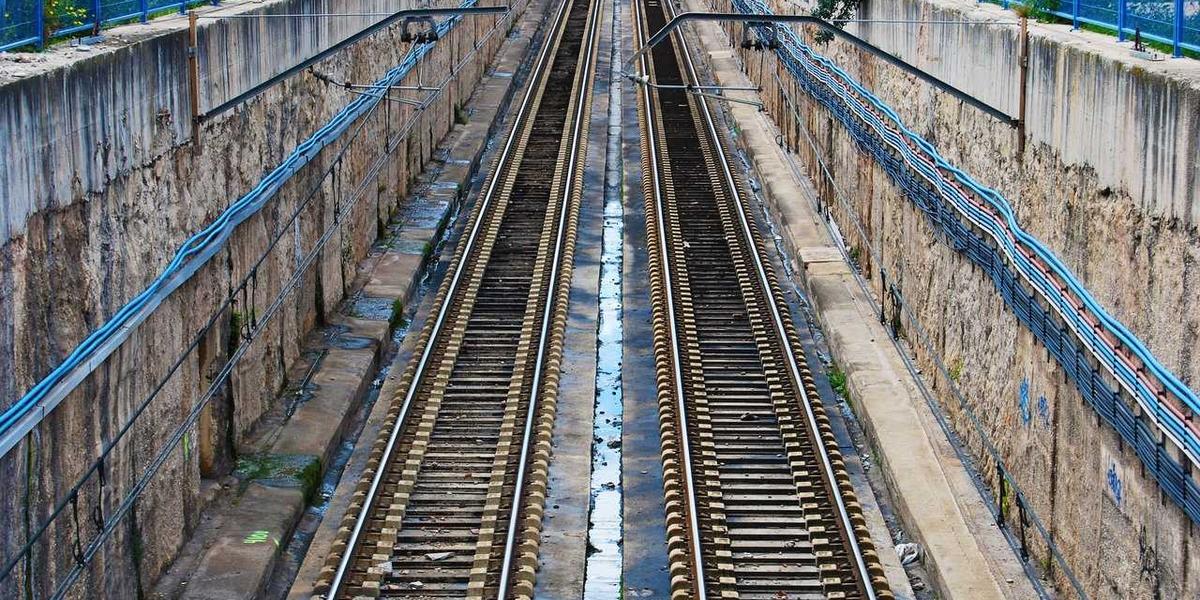 Parallel railway tracks running through a city — motion that never stops to think