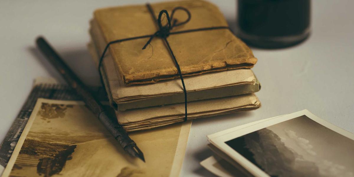 A stack of old letters and postcards tied with string — documents that must survive decades of changing technology