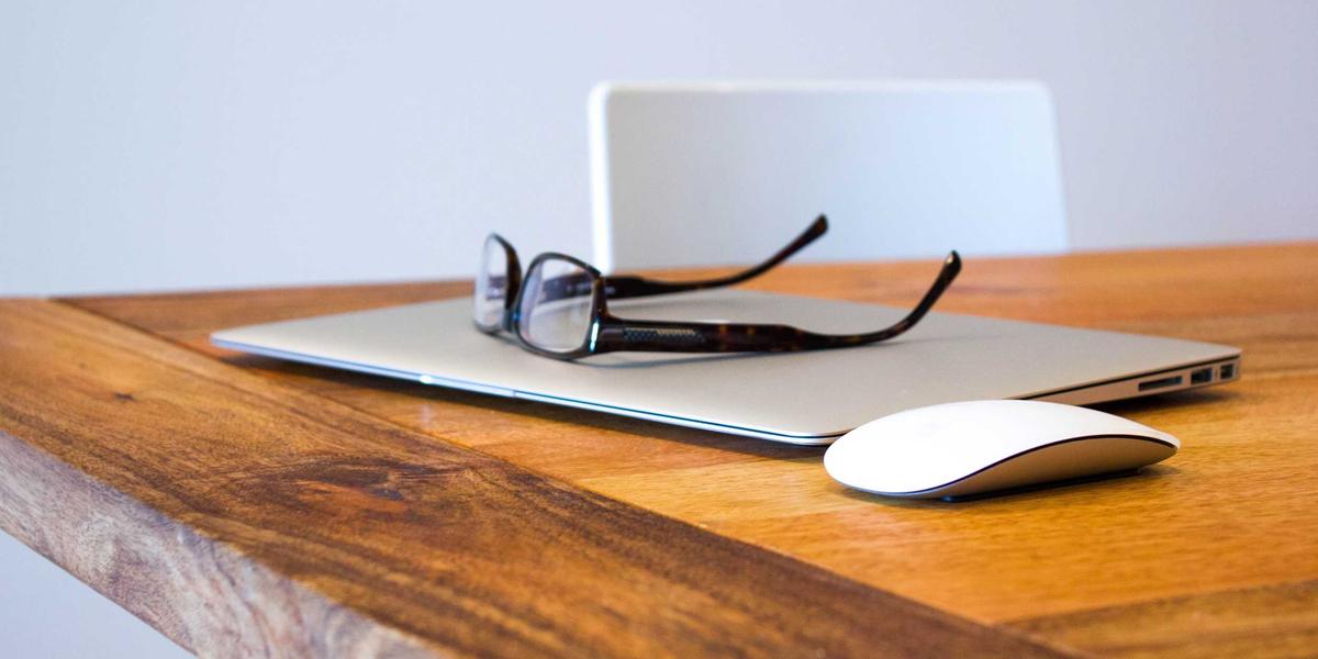 A laptop and reading glasses on a desk — merging PDFs locally keeps documents private
