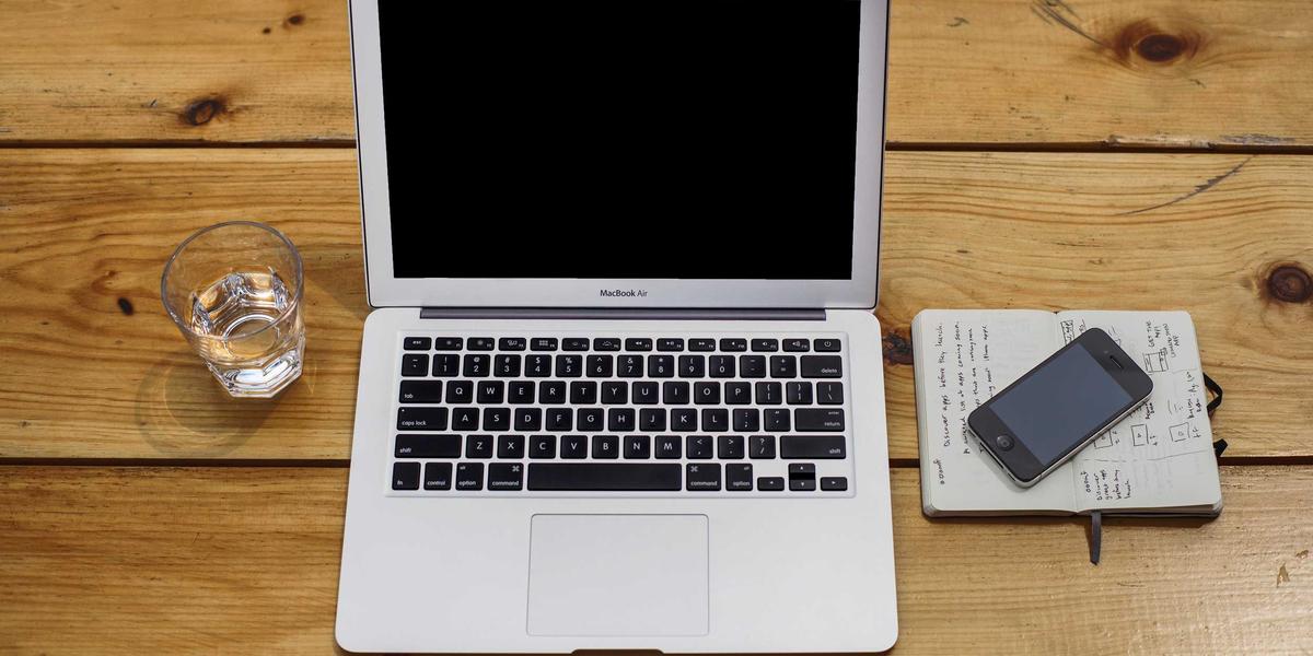 A laptop with a notebook and pen — sign PDFs locally before they leave your device